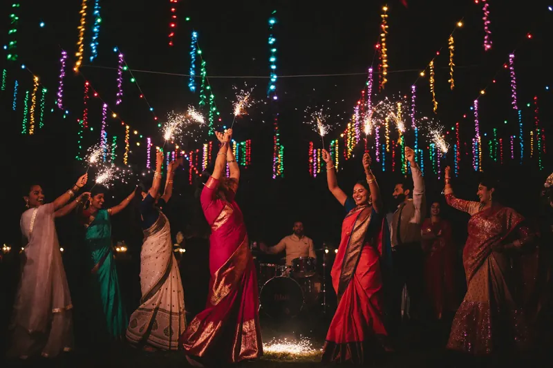 Guests dancing with sparklers beneath colourful lights