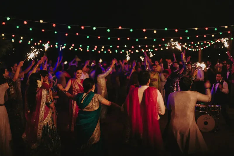A crowd dancing beneath strings of coloured lights