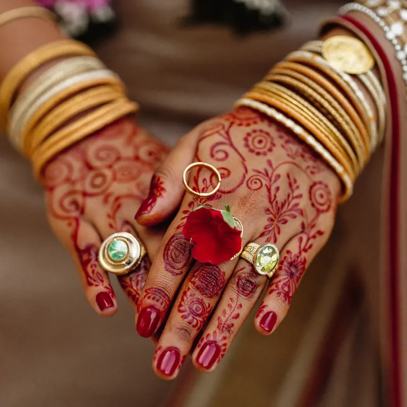 Henna-decorated hands with bangles and rose petals